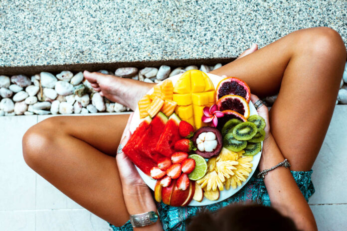 Girl,Relaxing,And,Eating,Fruit,Plate,By,The,Hotel,Pool.