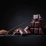 Chocolate Has Hidden Heart Benefits A pile of dark chocolate bars with cocoa powder on a black surface