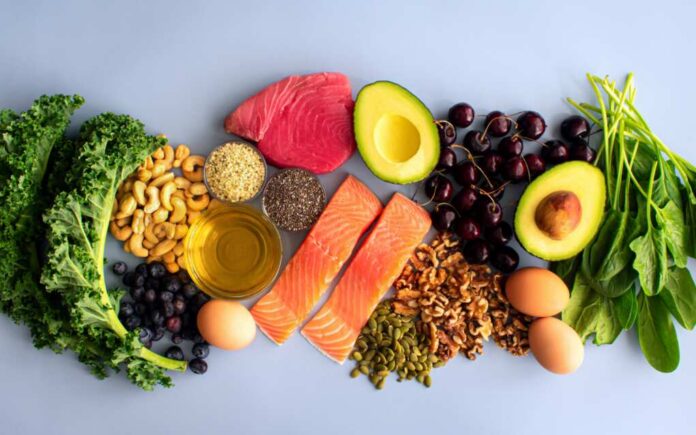 shutterstock_2131483793.jpg An assortment of healthy foods including fish, nuts, fruits, and vegetables arranged on a light background
