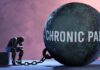 A figure representing chronic pain, sitting beside a large ball labeled 'CHRONIC PAIN' chained to their body