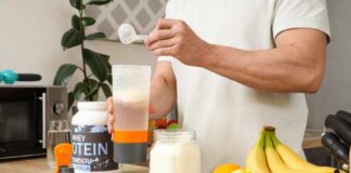 Person preparing a protein shake with fruits and whey protein powder in a kitchen