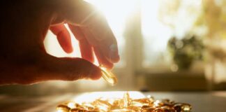 A hand reaching for a golden capsule among many on a table