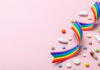 Colorful pills and a rainbow ribbon on a pink background