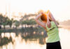 Back Pain SOLVED: Dumbbell Hack You Need! A woman stretching her arms by a lake during sunrise