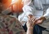 A doctor holding the hand of an elderly patient during a consultation