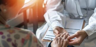 A doctor holding the hand of an elderly patient during a consultation