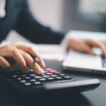 Desk Workers’ Secret WEAPON Against Health Risks A business professional using a calculator while working on a laptop