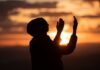 Silhouette of a person with raised hands against a sunset