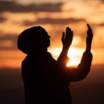 Optimism’s Secret Power: Shields Against Stroke Damage Silhouette of a person with raised hands against a sunset