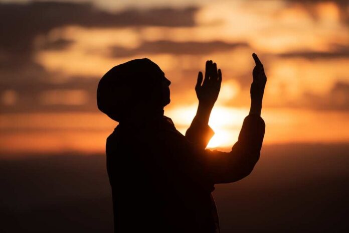 Silhouette of a person with raised hands against a sunset